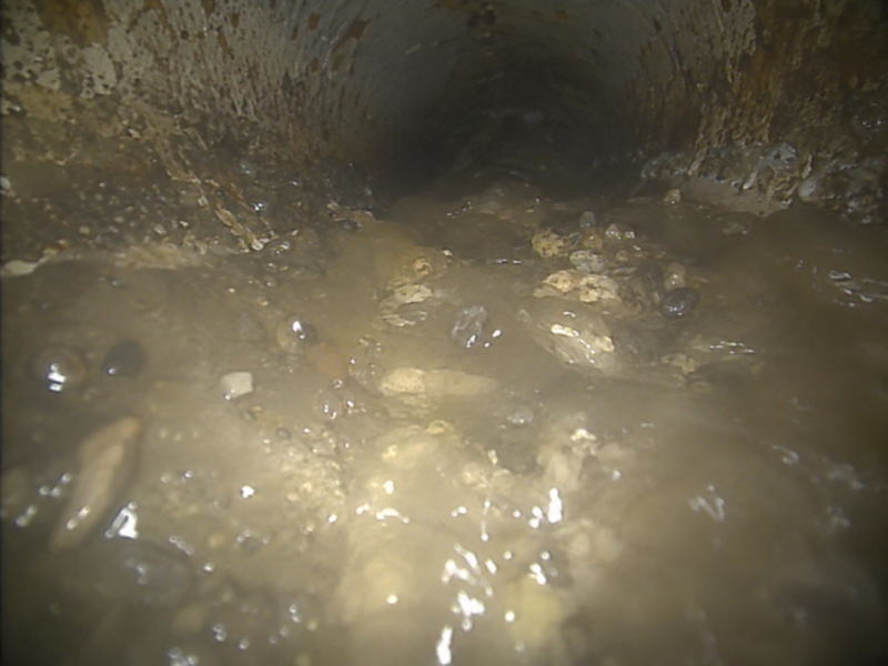 View from a drain survey camera showing a pipe blocked with silt and debris, with no visibility beyond the obstruction